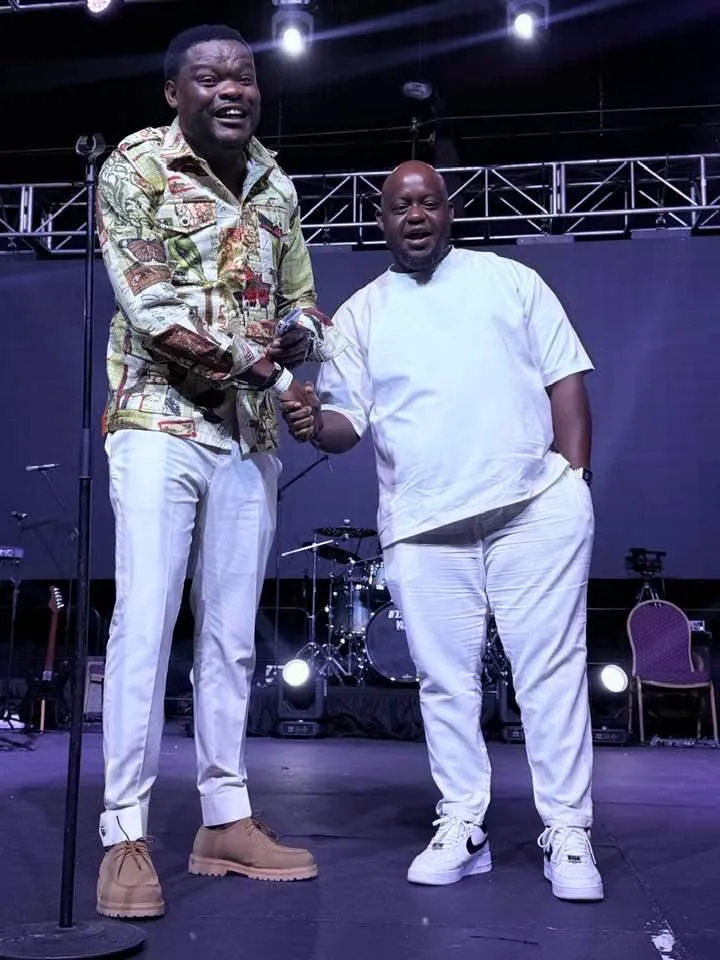Oscar in all white on stage with a fellow comedian